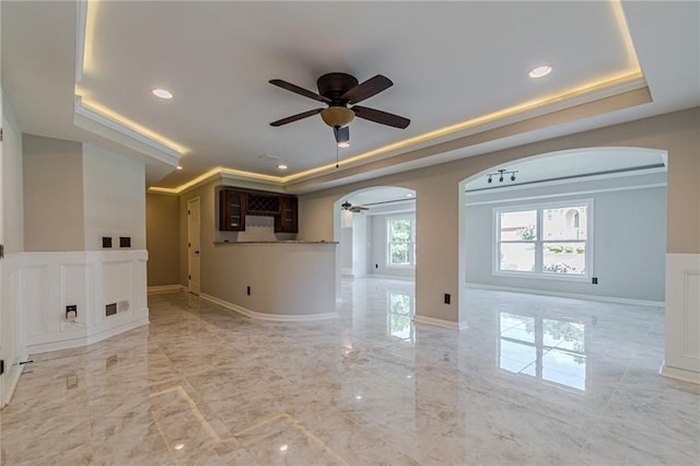 unfurnished living room featuring a raised ceiling and ceiling fan