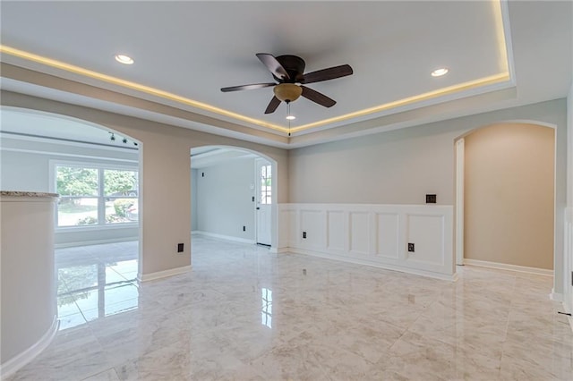 empty room featuring ceiling fan and a tray ceiling