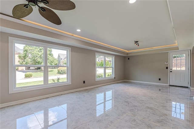 interior space with a raised ceiling, a wealth of natural light, and ceiling fan