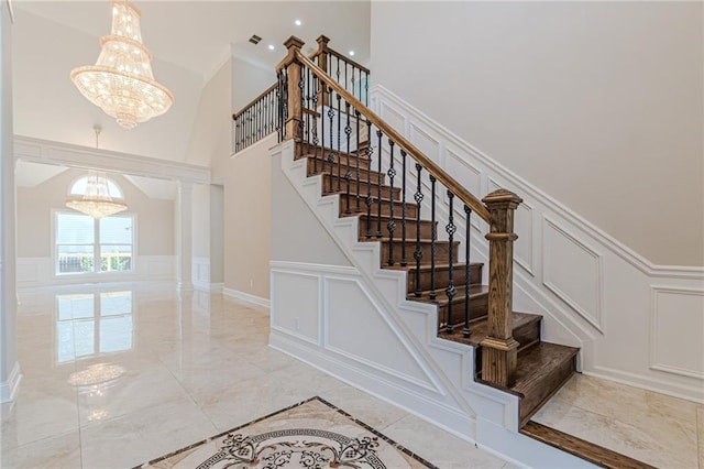 stairway featuring decorative columns and a notable chandelier