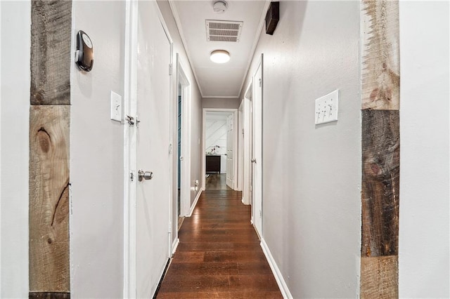 hallway featuring dark wood-style flooring, baseboards, and visible vents