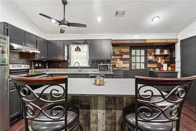 kitchen featuring visible vents, a breakfast bar area, under cabinet range hood, a sink, and appliances with stainless steel finishes