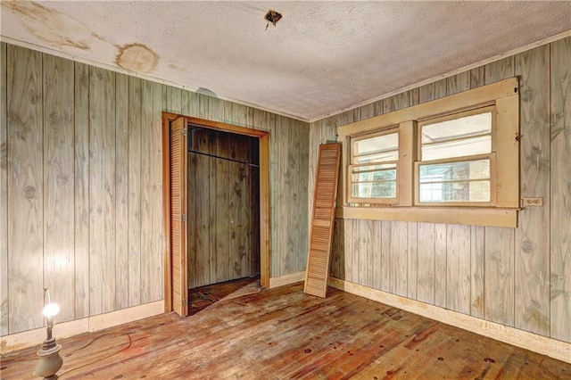 6191 Cumming Hwy, Canton, GA 30115 - empty room featuring hardwood / wood-style floors, a textured ceiling, wooden walls, and baseboards