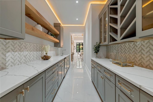 kitchen featuring marble finish floor, gray cabinets, open shelves, glass insert cabinets, and light stone countertops