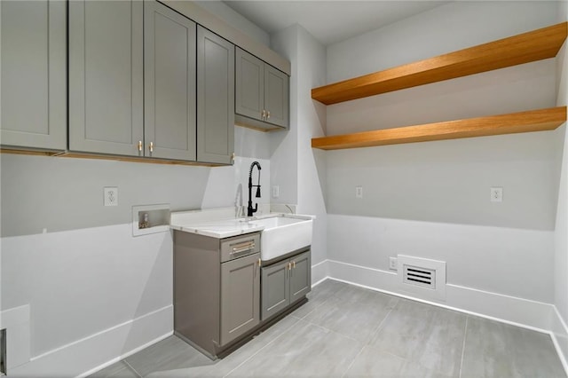 washroom with visible vents, washer hookup, a sink, cabinet space, and baseboards