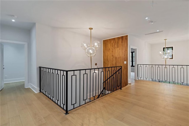 hall featuring an inviting chandelier, wood finished floors, an upstairs landing, and baseboards