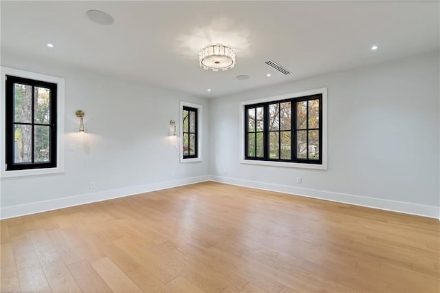 spare room with a wealth of natural light, visible vents, light wood-style flooring, and baseboards