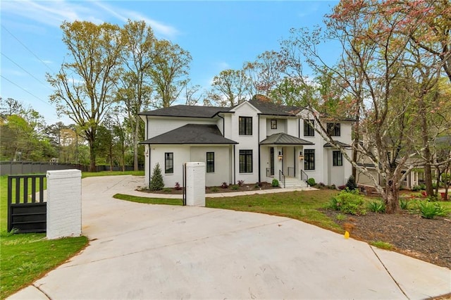 modern farmhouse with stucco siding, driveway, fence, a front yard, and a shingled roof