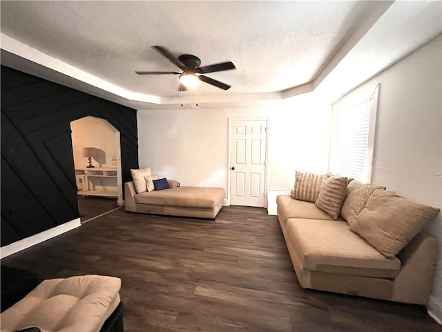 living room with a tray ceiling, ceiling fan, a textured ceiling, and dark hardwood / wood-style floors