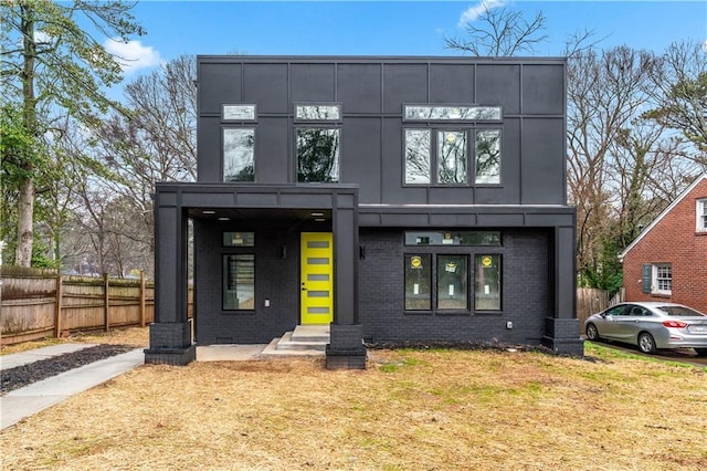 contemporary house with a front yard, brick siding, fence, and entry steps