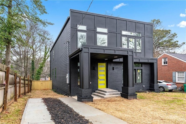 contemporary house featuring brick siding and fence