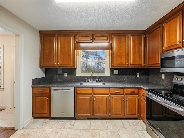 kitchen featuring appliances with stainless steel finishes, sink, backsplash, and dark stone counters