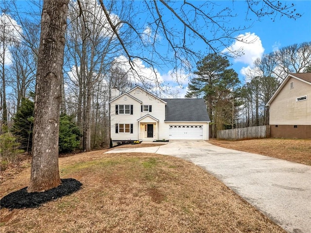 traditional home with a garage, a shingled roof, fence, driveway, and a front lawn