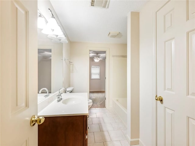 bathroom with tile patterned floors, toilet, a textured ceiling, vanity, and a bathtub