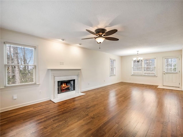 unfurnished living room with ceiling fan with notable chandelier, a textured ceiling, and dark hardwood / wood-style flooring