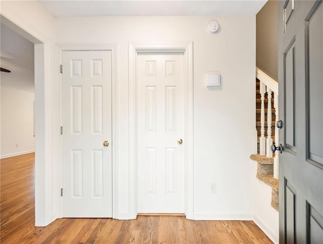 entrance foyer featuring light wood-type flooring, stairs, and baseboards