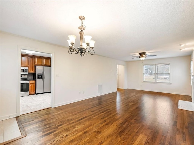 unfurnished living room with ceiling fan with notable chandelier, a textured ceiling, and light wood-type flooring