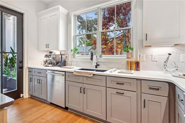 kitchen featuring white cabinetry, gray cabinetry, dishwasher, light hardwood / wood-style flooring, and sink