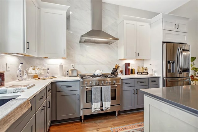 kitchen featuring appliances with stainless steel finishes, exhaust hood, white cabinetry, gray cabinets, and light wood-type flooring