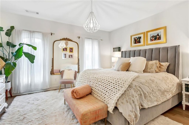 bedroom with light hardwood / wood-style floors and a notable chandelier