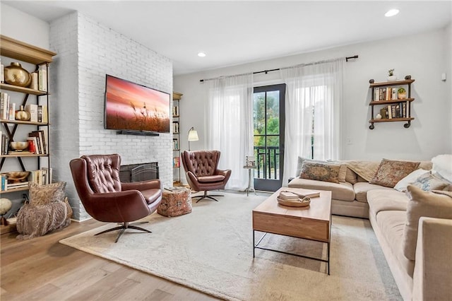 living room with light wood-type flooring and a brick fireplace