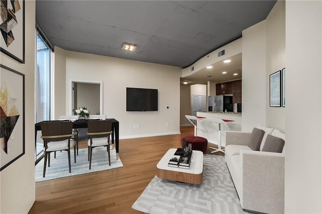 living room with light wood-type flooring, baseboards, and visible vents