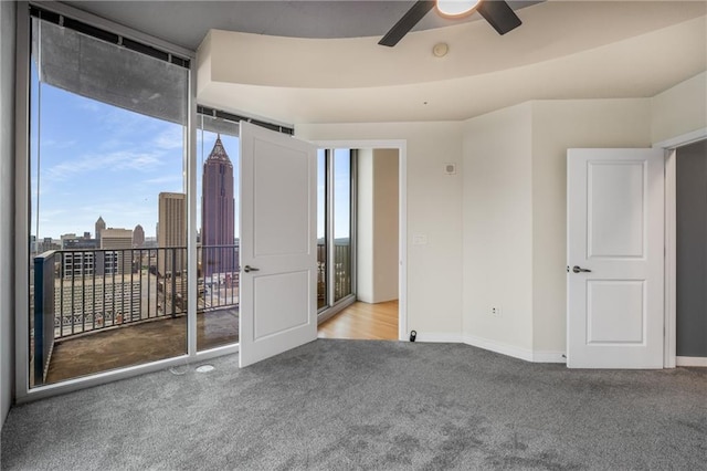 carpeted spare room featuring baseboards, ceiling fan, and a city view