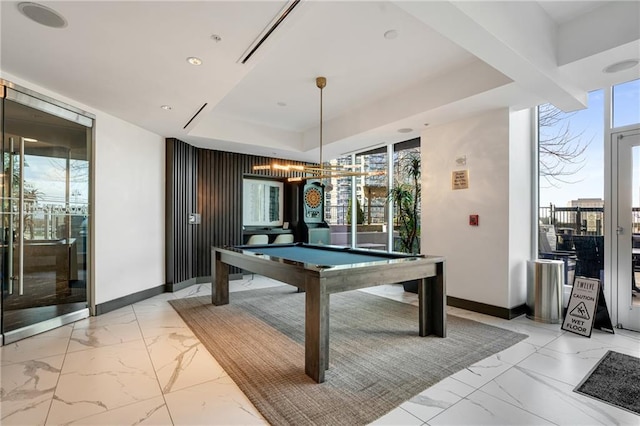 game room featuring marble finish floor, a tray ceiling, a wealth of natural light, and baseboards