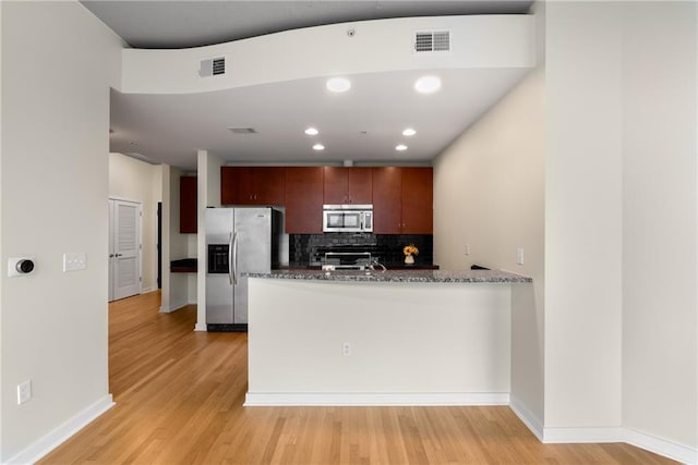 kitchen with stainless steel appliances, visible vents, backsplash, and light wood finished floors