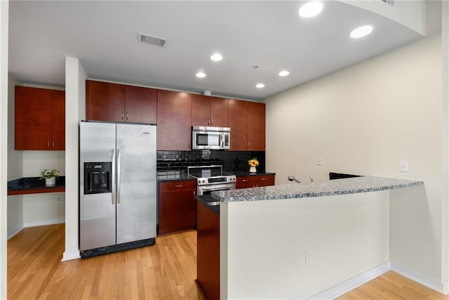 kitchen with tasteful backsplash, light wood-style flooring, a peninsula, stainless steel appliances, and recessed lighting