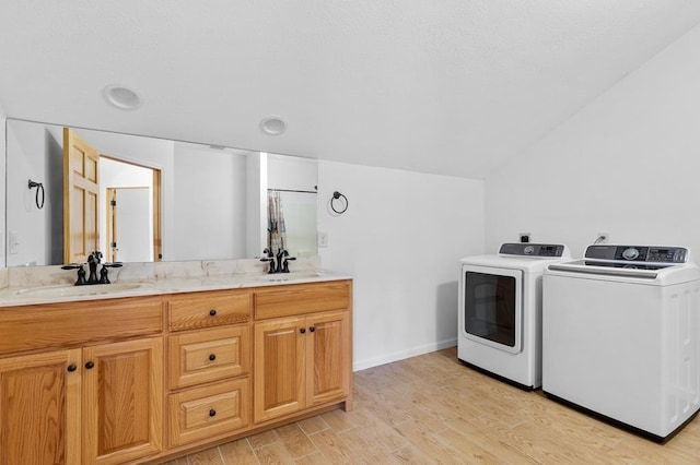 laundry area featuring sink, washing machine and clothes dryer, and light hardwood / wood-style floors