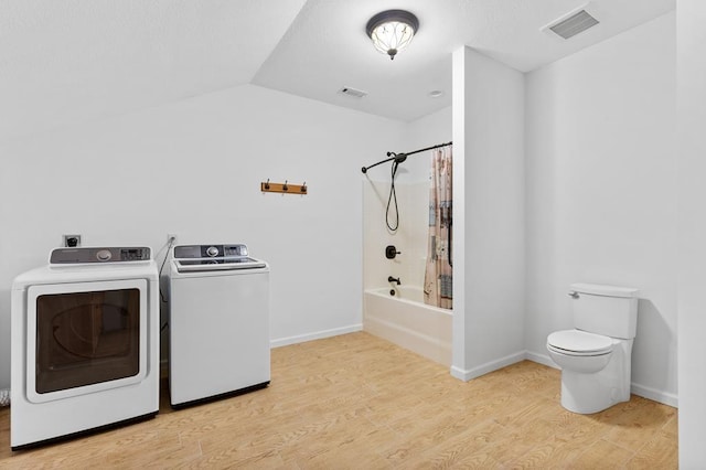 clothes washing area with washing machine and dryer and light hardwood / wood-style flooring