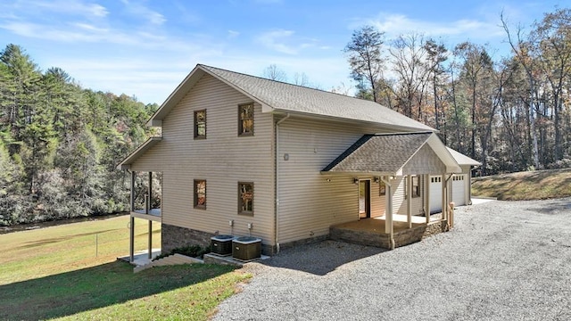 view of side of home featuring a garage, cooling unit, and a lawn