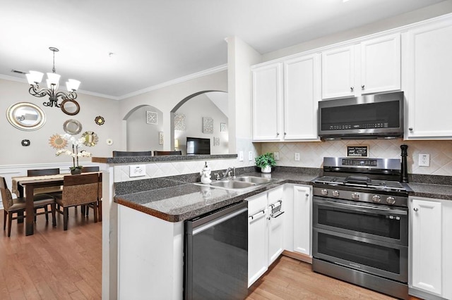kitchen with appliances with stainless steel finishes, ornamental molding, a sink, white cabinetry, and light wood-type flooring