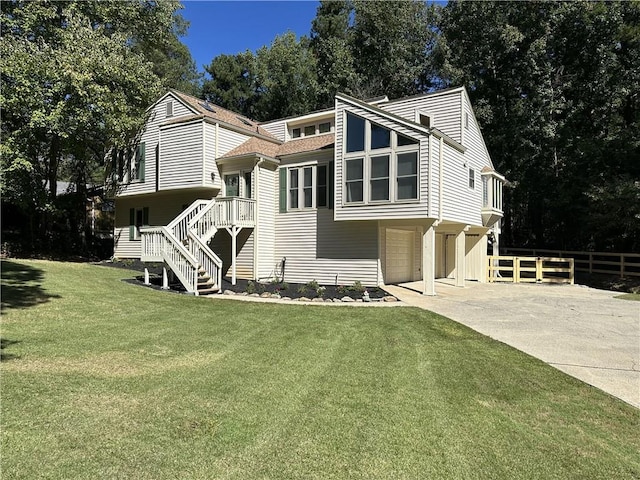 view of front of property with an attached garage, concrete driveway, a front yard, and fence