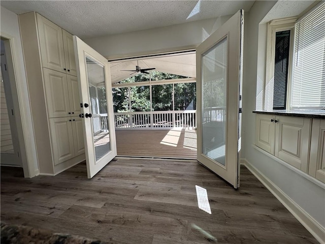 doorway to outside featuring baseboards, dark wood finished floors, a textured ceiling, and french doors