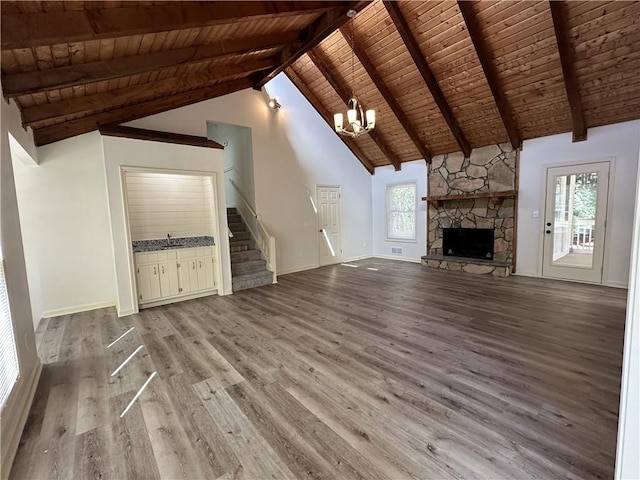 unfurnished living room featuring a fireplace, wood finished floors, wood ceiling, stairs, and beam ceiling