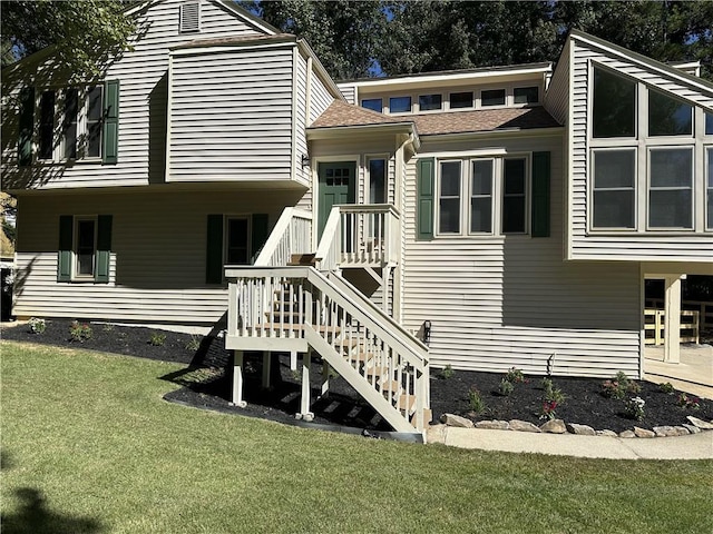 rear view of house featuring a lawn and stairs