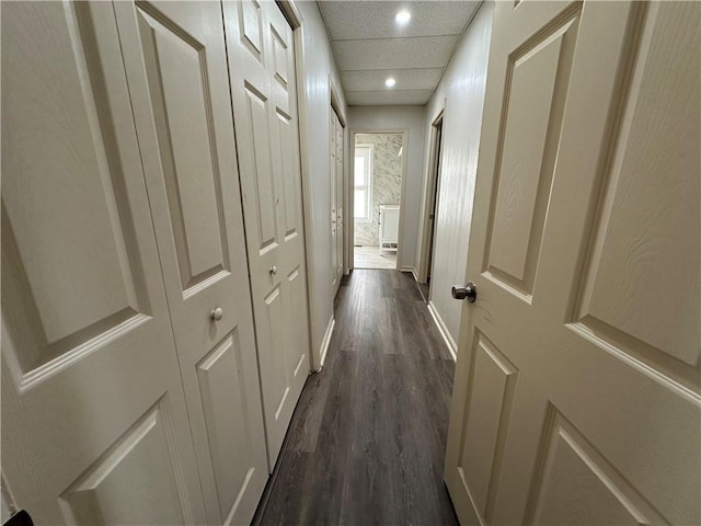 hallway featuring baseboards, dark wood-style flooring, a drop ceiling, and recessed lighting