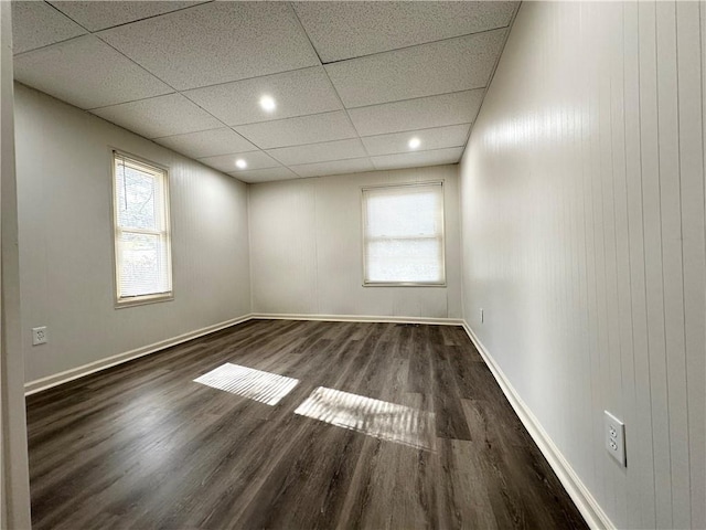 spare room with wood finished floors, a paneled ceiling, and baseboards