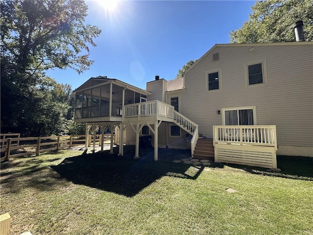 rear view of property featuring a lawn, a sunroom, stairs, fence, and a deck