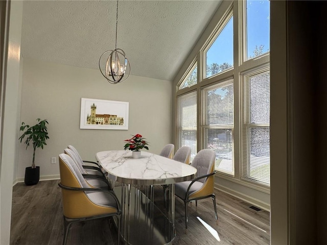 dining area featuring lofted ceiling, a chandelier, a textured ceiling, wood finished floors, and baseboards