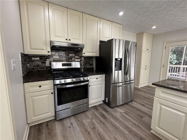 kitchen with stainless steel appliances, backsplash, wood finished floors, and under cabinet range hood