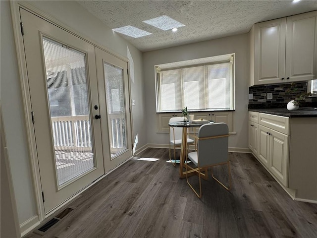 interior space featuring dark wood-style floors, french doors, visible vents, a textured ceiling, and baseboards