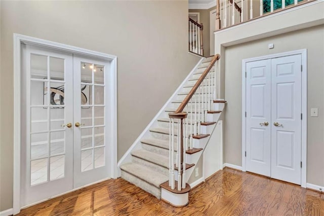 staircase with french doors, crown molding, and hardwood / wood-style floors