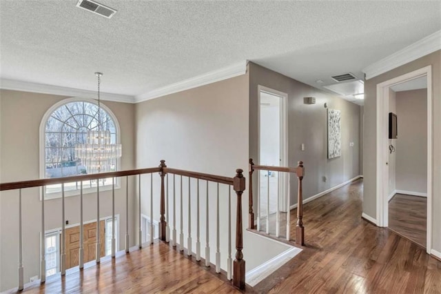 hall featuring hardwood / wood-style floors, crown molding, a chandelier, and a textured ceiling