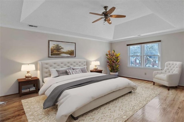 bedroom featuring ceiling fan, hardwood / wood-style floors, and a raised ceiling