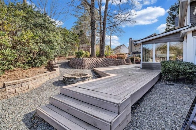 exterior space with a wooden deck and an outdoor fire pit