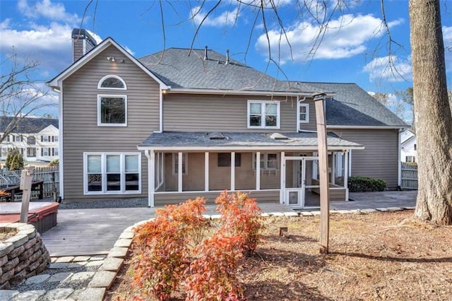 rear view of house with a hot tub, a patio area, and a sunroom