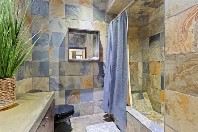 bathroom featuring tiled shower, toilet, and vanity